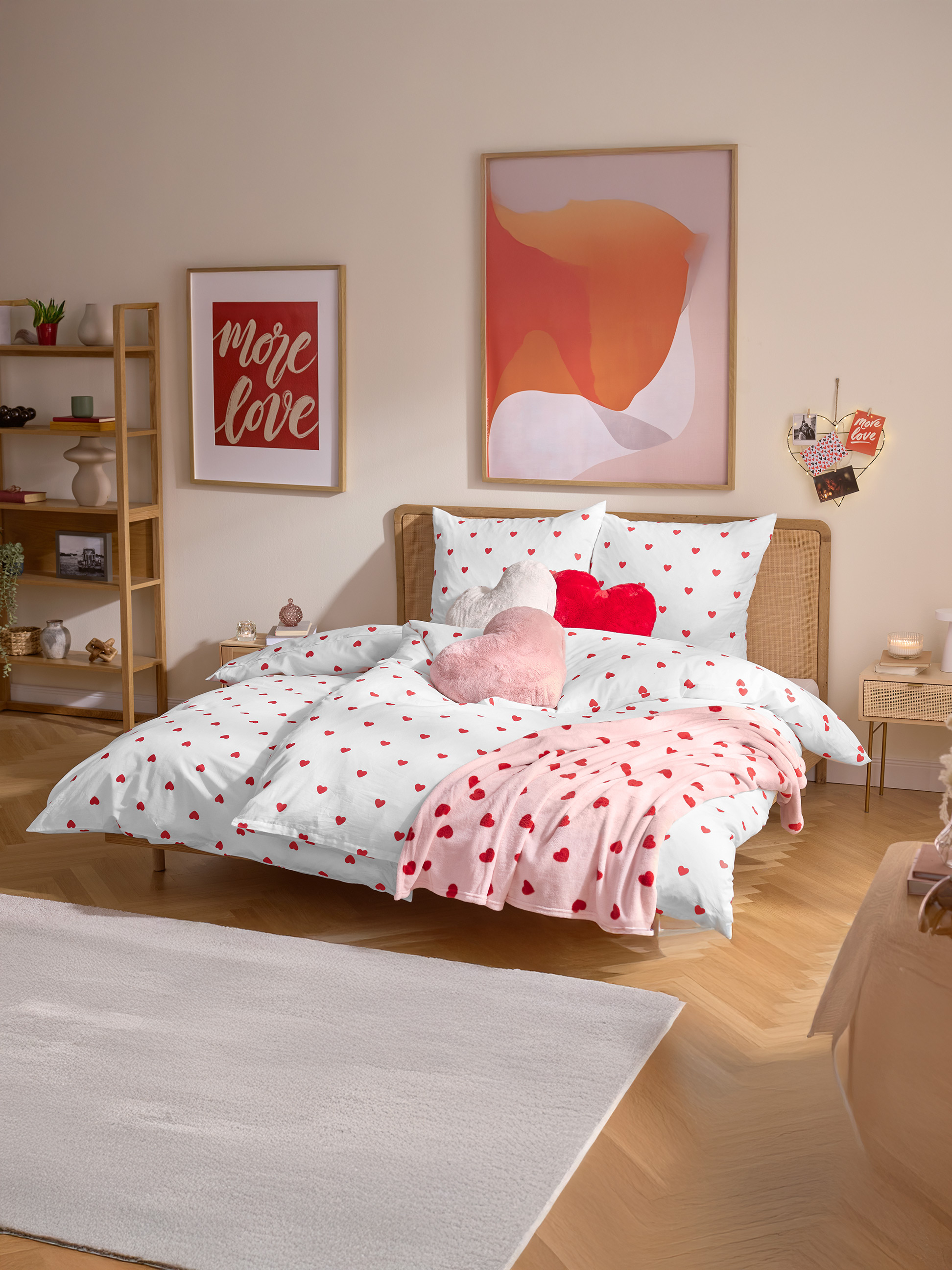 Schlafzimmer mit Herz-Bettwäsche, einer rosa Decke und herzförmigen Kissen.