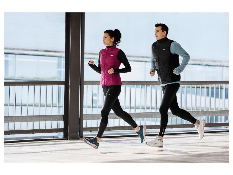 Zwei Personen in Sportkleidung rennen in einer städtischen Umgebung.