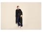 Frau in schwarzem Trenchcoat, Wide-Leg-Jeans und weißen Sneakern.