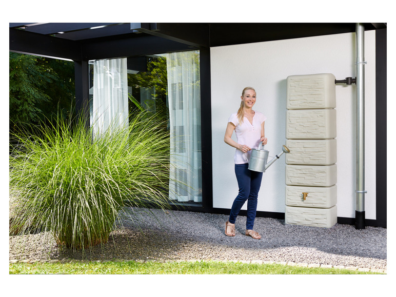 Eine Frau mit einer Gießkanne vor einem Regenwassertank