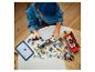 Kind baut Lego-Autos und -Figuren an einem Tisch mit Tablet.