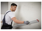 Ein Mann in Arbeitskleidung benutzt eine Bosch-Wasserwaage, um eine Wand zu befestigen.