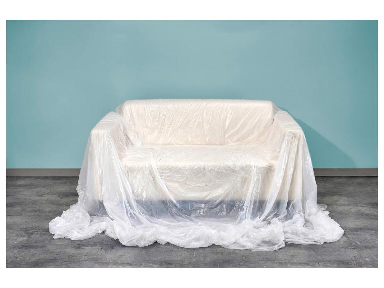 Sofa mit Schutzfolie vor einer blauen Wand und Betonboden