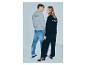 Zwei junge Leute tragen graue und schwarze Sweatshirts mit Text auf dem Rücken und Jeans oder schwarze Hosen.