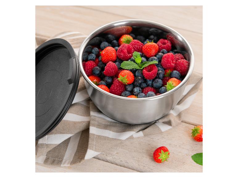 Edelstahlschale mit frischen Beeren und schwarzem Deckel auf Holz.