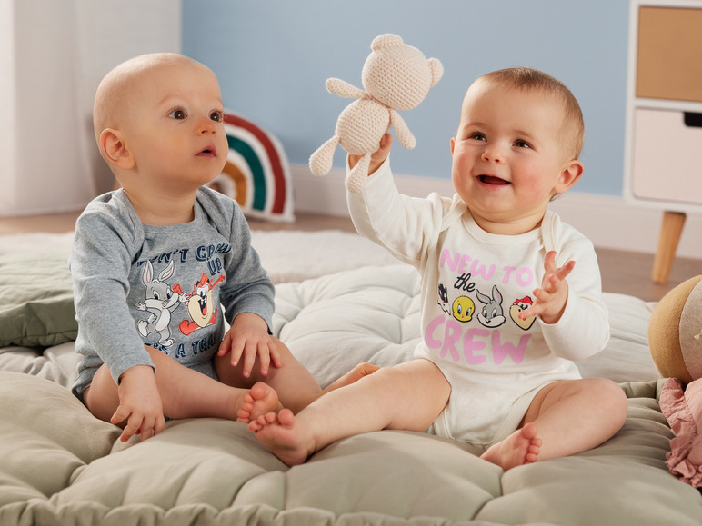 Zwei Babys tragen Looney Tunes Strampler.