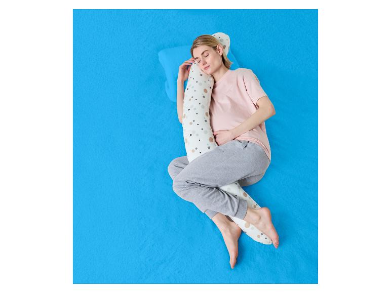 Frau schläft auf der Seite mit einem Seitenschläferkissen auf einem blauen Laken.