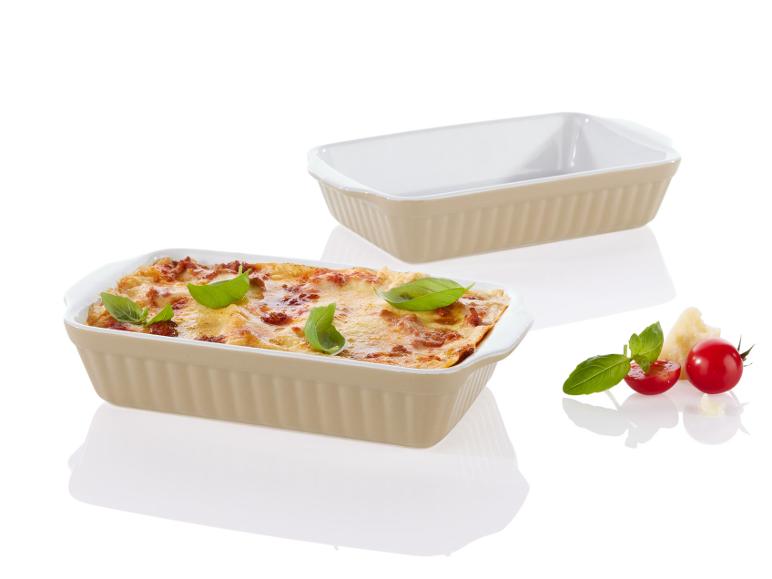 Lasagne in einer beige Auflaufform, mit zusätzlicher Auflaufform und Zutaten.
