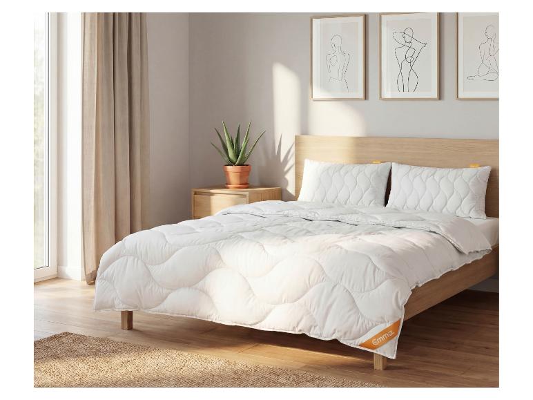 Schlafzimmer mit weißer Bettdecke und Kissen, Holzbett, Nachttisch und Pflanze.