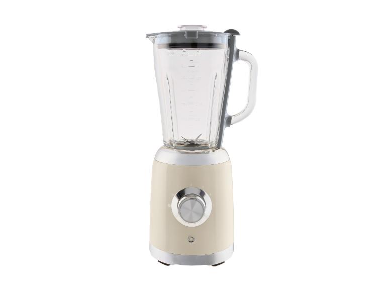 Cremefarbener Mixer mit Glaskrug und silbernem Bedienknopf.