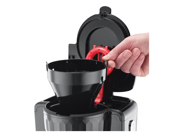 Hand setzt schwarzen Kaffeefilter in Kaffeemaschine ein.