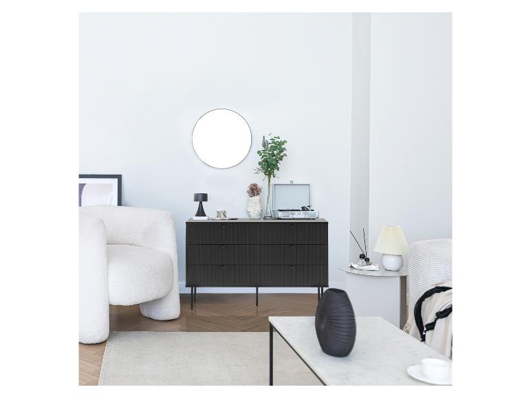Schwarze Kommode, runder Spiegel, weißer Sessel und Plattenspieler im Wohnzimmer.