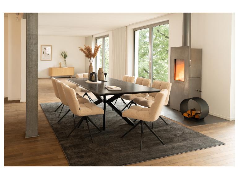 Modernes Esszimmer mit schwarzem Esstisch, beigen Stühlen und Beton-Kamin.