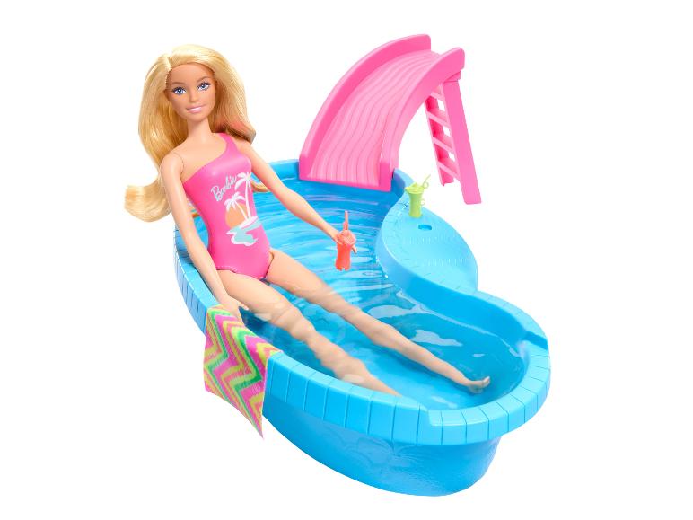 Puppe im pinken Badeanzug entspannt in einem blauen Pool mit Rutsche.