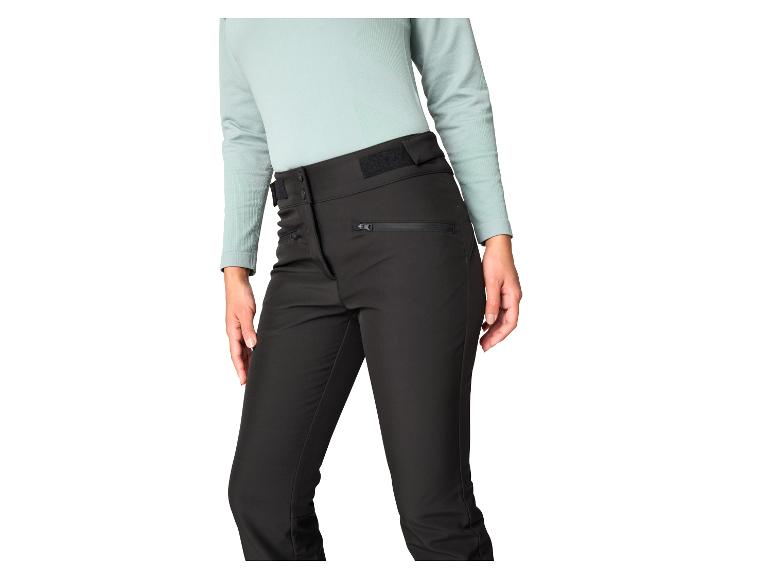 Schwarze Outdoor-Hose mit Reißverschlüssen und einem hellgrünen Langarmshirt.