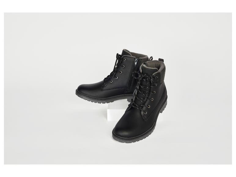 Zwei schwarze Stiefel, einer auf einem weißen Podest, der andere auf dem Boden.