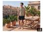Ein Mann in Poloshirt und ESMARA MEN Shorts auf einer sonnigen Terrasse. [KI-generiertes Bild]