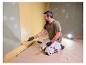 Mann streicht Wand, beleuchtet von LIVARNO® Arbeitsleuchte „The Painter+“.