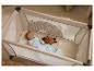 Baby schläft in einem Laufstall mit Schnuller und leuchtendem Plüschtier.