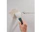 Hand hält Spachtel, kratzt Wand mit Riss und abblätterndem Putz ab.