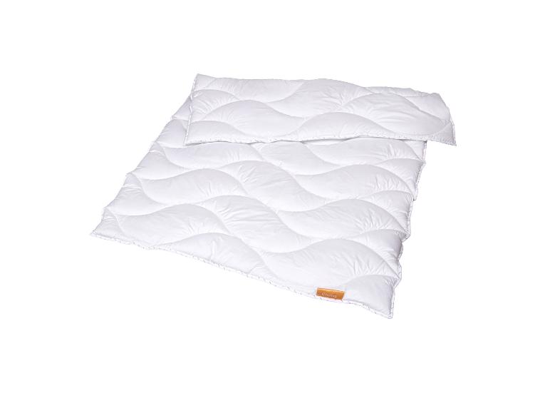 Weiße Steppdecke mit Wellenmuster und orangefarbenem Etikett.