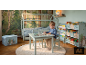 Kinderzimmer mit Hausbett, kleinem Tisch und Stühlen sowie Bücherregalen.