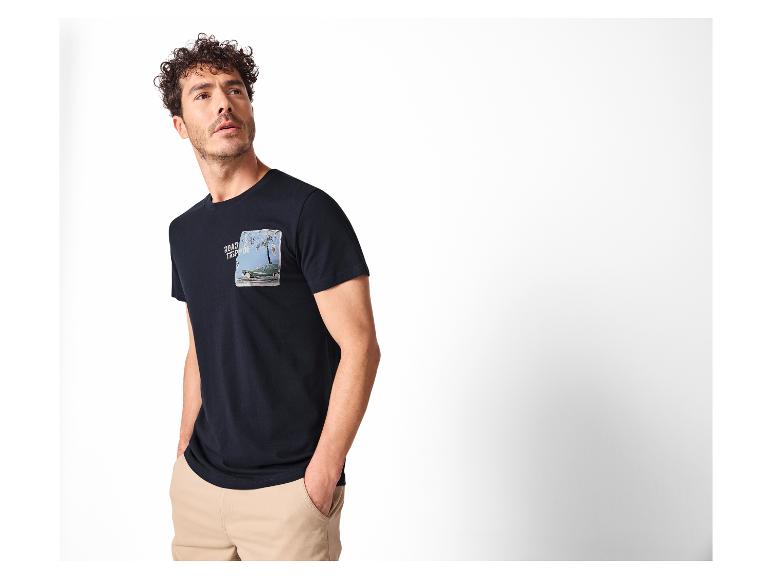 Mann in marineblauem T-Shirt mit Auto- und Palmenprint und beiger Hose.