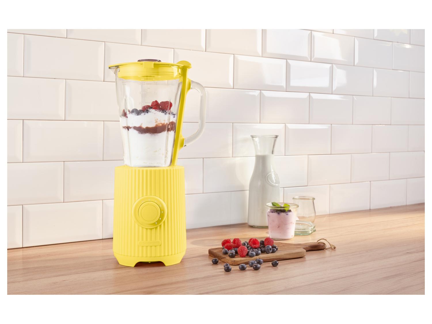 Gelber Mixer in der Küche mit Beeren und Joghurt, bereit für einen Smoothie.