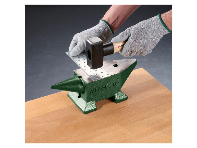 Eine Hand schlägt mit einem Hammer auf ein Blech auf einem Parkside Amboss.
