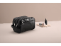Schwarze Kulturtasche mit einer kleinen Flasche und Pinsel auf einem Handtuch.