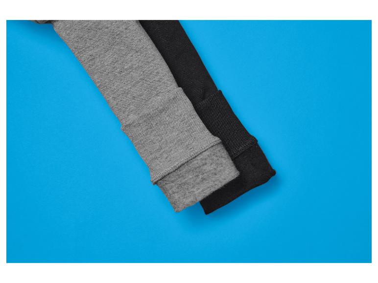 Zwei Pulloverärmel, einer grau und einer schwarz, auf blauem Hintergrund.