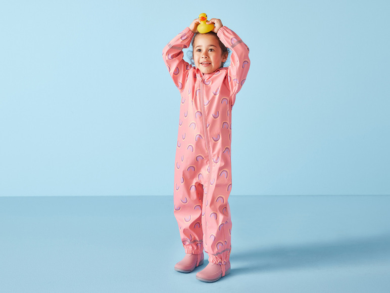 Ein Kind trägt einen rosafarbenen Regenanzug mit Regenbogenmuster.