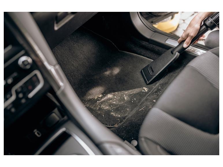 Staubsaugen des Autoinnenraums mit einem Handstaubsauger.