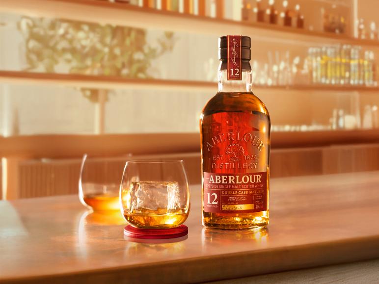 Eine Flasche 12 Jahre alter Single Malt Scotch Whisky und ein Glas mit Eis an einer Bar.