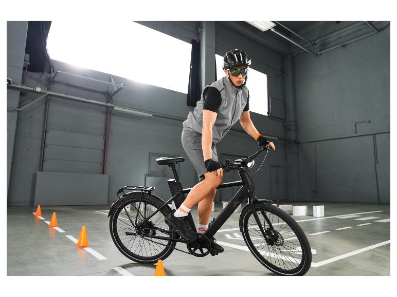 Mann in reflektierender Weste und Radbrille auf einem Fahrrad, übt das Fahren zwischen Pylonen.