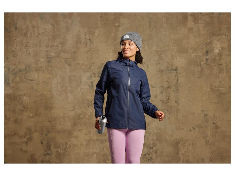 Eine Frau trägt eine blaue Regenjacke und rosafarbene Leggings.