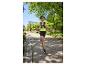 Frau in Sport-T-Shirt und Laufshorts, mit Laufrucksack, joggt in einem Park.