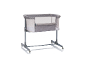 Graues Babybett mit Netzseiten und Rollen