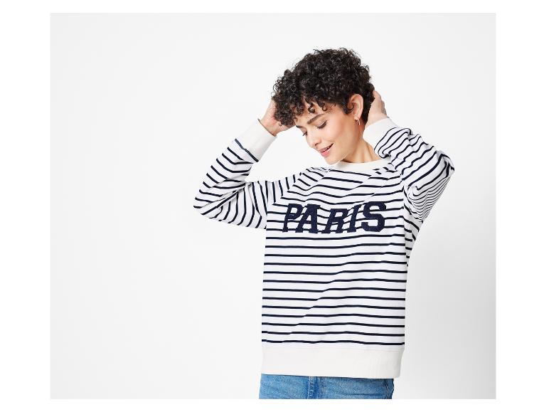 Eine Frau trägt einen gestreiften Pullover mit dem Schriftzug 'Paris'