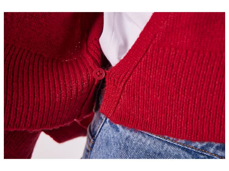Rote Strickjacke mit Knöpfen, getragen über einem weißen T-Shirt und Jeans.