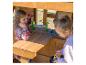 Mädchen spielen mit Spielzeug in einer Outdoor-Holzspielküche.