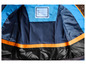 Die Innenseite einer blauen Jacke mit orangefarbenem Rand und einem Namensschild.