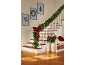 Weihnachtsgirlande mit Lichtern und roter Schleife schmückt eine Treppe, mit festlicher Wandkunst.