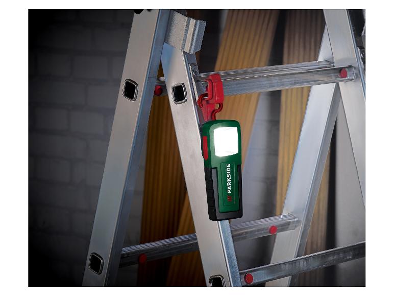 Eine Parkside Arbeitsleuchte hängt an einer Metallleiter und beleuchtet einen dunklen Hintergrund.