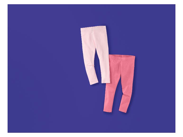 Zwei Kinderleggings, eine hellrosa und eine dunkelrosa, auf lila Hintergrund.