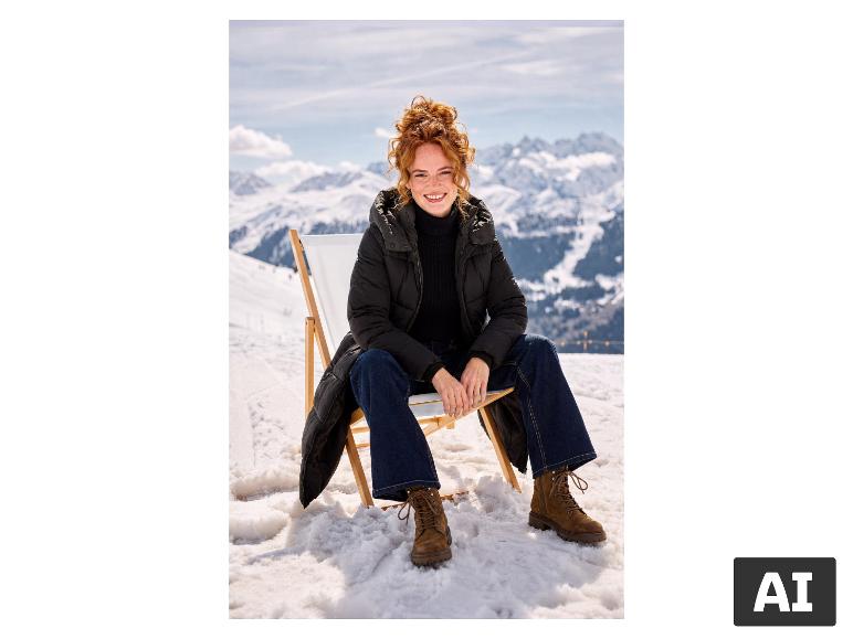Frau im schwarzen ESMARA® Strickpullover sitzt auf einem Liegestuhl in den verschneiten Bergen. [KI-generiertes Bild]