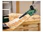 Grüner Akku-Gebläse reinigt Holzspäne von einer Holzwerkbank.