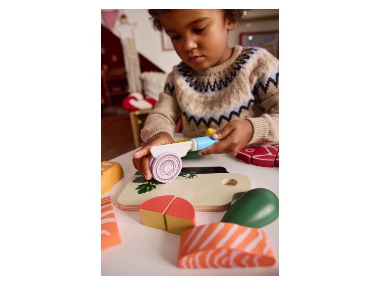 Kind spielt mit Spielzeugessen und Schneidebrett.