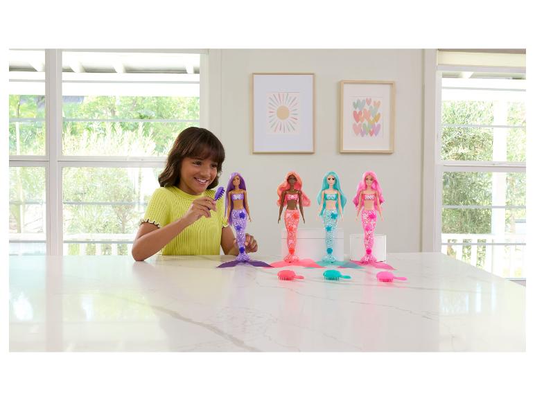 Ein Mädchen bürstet das Haar einer Meerjungfrauenpuppe, mit drei weiteren Meerjungfrauenpuppen und Bürsten auf einem Tisch.