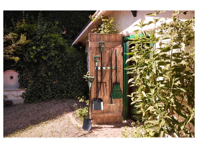 Gartengeräte hängen an einer Holzwand außerhalb eines Gartenhauses.